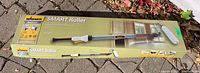Full boxed view of Wagner Smart Roller 9-inch wall and ceiling paint roller with telescopic handle, placed on ground with leaves.