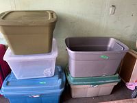 Stacked plastic storage bins in various colors including tan, blue, translucent white, grey, purple, and green.