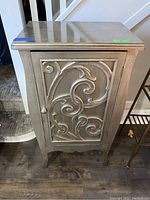 Front view of decorative wooden hall table showing detailed scroll design on front door panel and overall shape.