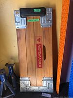 Top view of the wooden Motomaster garage creeper with metal reinforcements and logo, showing the 36x15 inch dimensions.