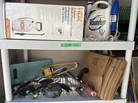 Full view of lot showing 2 gallon HDX sprayer, Roundup herbicide container, brown lawn bags, and various tools in basket below