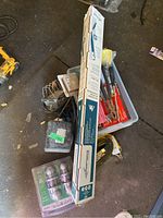 Lot overview showing boxed Worsports long handle tool, assorted hand tools, hardware containers on garage floor