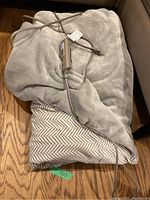 Sunbeam heated blanket folded with attached power cord and controller laid on hardwood floor.