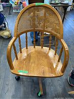 Front view of oak office chair showing cane backrest, wooden seat, and armrests