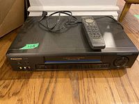 Front and top view of Panasonic PV-7661 VHS VCR with remote on top, showing overall condition and power cord.
