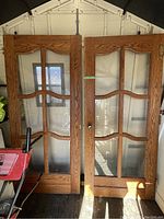 Pair of solid wood French doors with glass panels shown standing upright indoors.