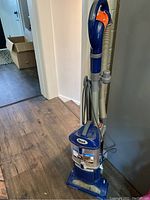 Full upright view of Shark vacuum showing blue body, handle, and cord wrapped on side.