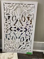 Mirror backed wall hanging with intricate floral and leaf carvings painted white