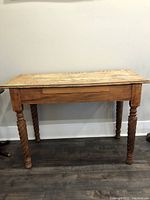 Full front view of rustic wooden desk showing turned legs and wood surface.