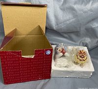 Opened red Fitz and Floyd box with two ceramic salt and pepper shakers in molded white styrofoam.