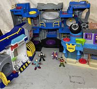 Front view showing two large plastic police-themed playsets and four small Imaginext figures in front