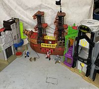 Wide view showing the pirate ship playset with figures and surrounding buildings including Batman building and city building.