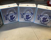 Three boxed tea pots shown side by side, each box features an image of the tea pot on the front, highlighting the octagonal shape and blue floral design.