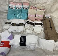 Various packaged socks arranged including blue Marant socks, Pink Rabbit beige socks with stripes, multiple packs of white socks, and a pair of brown argyle dress socks.