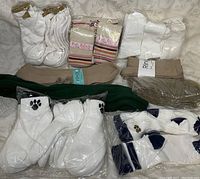 Photo showing assortment of packaged white ankle socks, striped pastel socks, beige and olive brown socks, green socks, white socks with black paw prints, and white socks with navy blue stars.