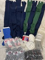A variety of packaged socks laid out including long navy blue and green socks, children's socks with cartoon characters, and white athletic socks.