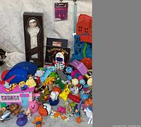 Overview photo showing vintage boxed doll, plastic treehouse playset, various small toys including talking phone and Pokémon ball, and many colorful plastic figurines scattered around