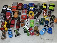 Wide view of assorted toy vehicles showing variety of cars, trucks, construction vehicles and character-themed toys in multiple colors and designs.