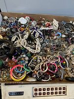 Image showing the full box with assorted broken jewelry pieces, beads, chains, and bracelets piled together.