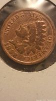 Close-up of the obverse side of the 1898 Indian Head Wheat Cent showing the date and Indian Head design, in protective cardboard holder.