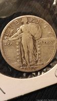 Obverse side of 1928 Standing Liberty quarter showing Liberty figure with shield, olive branch, date 1928, and inscriptions including LIBERTY and IN GOD WE TRUST.