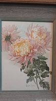 Close-up frontal image of one framed floral print with detailed pink and yellow flowers and green foliage.