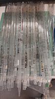 Top-down view of a variety of glass stirring and measuring sticks with measurement markings, neatly aligned on a flat surface.