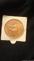 Copper Morgan dollar replica reverse view showing eagle with shield and inscriptions in copper tone, housed in white cardboard holder.