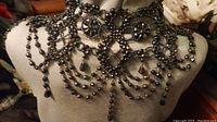 Full front view of the black beaded collar showing layered draped strands and beadwork detail