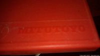Close-up photo of red plastic case with Mitutoyo branding embossed.