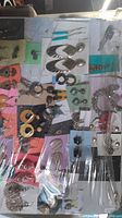 Photo showing several pairs of variously styled earrings on a colored card display with plastic wrap over the lot.