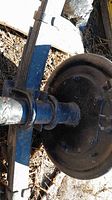 Close-up photo of the trailer axle with visible leaf springs and brake drum showing surface rust and dirt.