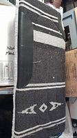 Photo of black and white striped horse blanket showing a leather patch reinforcement on the side and woven geometric patterns