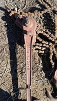 Close-up of lever marked 'SAFETY PULL' showing lever arm and part of chain lying on dirt ground