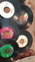 Five 45 RPM vinyl records with various labels showing condition and design