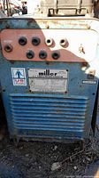 Front panel of Miller welder showing control knobs and connectors with rust and paint wear.