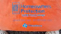 Orange bag with blue text 'Homeowners Protection Spill & Flood Package' and Fb Systems branding visible indicating the brand and intended use of the kit.