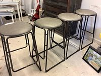 Four metal barstools arranged in a row showing the overall condition and style.