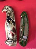 Photo showing front and side of two collectible pocket knives on a red surface; one with eagle and flag design, the other with circuit pattern