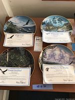 Set of four eagle-themed collector plates with certificates of authenticity displayed on a wooden surface.