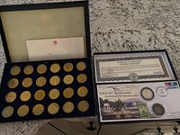 Set of 20 gold-colored transit tokens from 1984 Los Angeles Olympics in black case with blue velvet lining and certificate inserts seen inside lid.