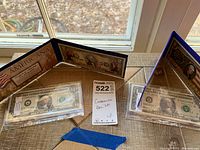 Full view of the two colorized bank notes in plastic holders with their accompanying triangular display stands showing Americana patriotic theme.