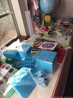 Photo showing blue magnetic fraction pieces including unit squares and strips, various educational items on a countertop under sunlight.