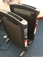 Two black Soleus micathermic portable electric heaters positioned side by side, showing the front mesh and side control knobs.
