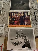 Black and white lobby card of submarine underwater scene and color lobby card of live-action characters at a garden.