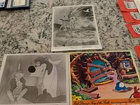 Three Disney movie memorabilia items on granite countertop, two black and white stills featuring Bambi and Song of the South characters, and one colored Song of the South lobby card