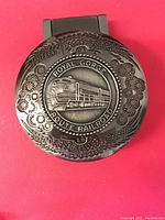 Close-up of metal embossed pocket watch lid featuring Royal Gorge Route Railroad steam locomotive design and decorative border.