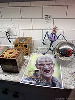 Photo showing two Hellraiser boxes, a signed Walking Dead photo, the alien statue, and the silver Phantasm orb on marble countertop.
