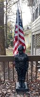 Full view of plaster US soldier statue on deck with American flag behind it
