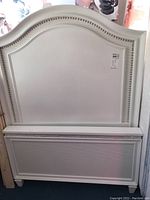 Front view of white twin bed frame headboard showing nail head and rhinestone decorative border.